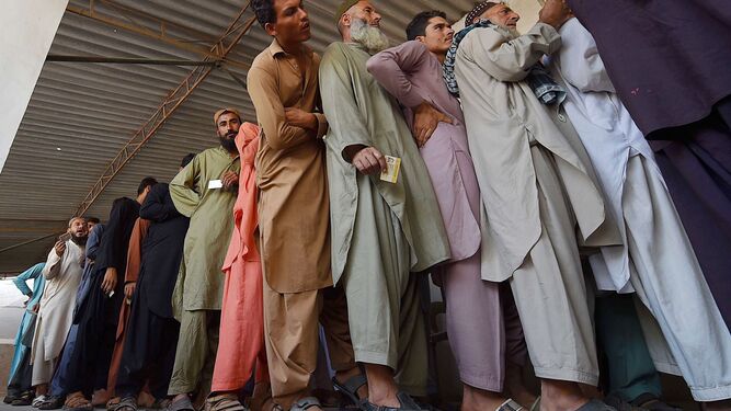 Un grupo de hombres afganos hacen cola en un campo de detención para su verificación.