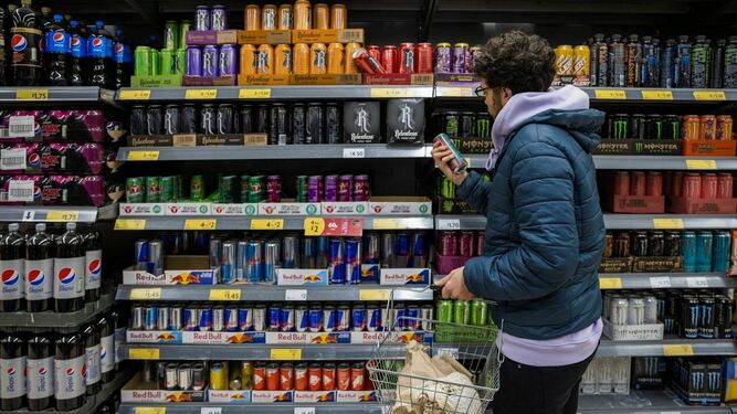 Un joven mira la sección de bebidas  energéticas  en el supermercado.