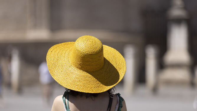 Una turista se cubre del sol con un sombrero.