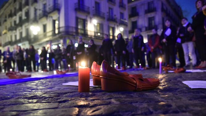 Zapatos rojos y una vela durante una concentración con la violencia machista.