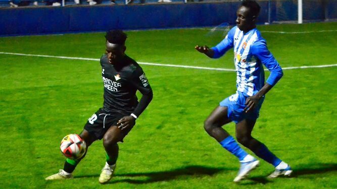 Mawuli con el balón controlado presionado por un defensa del Águilas FC.
