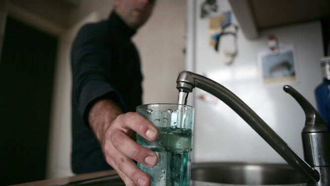 Un hombre llena un vaso de agua del grifo.