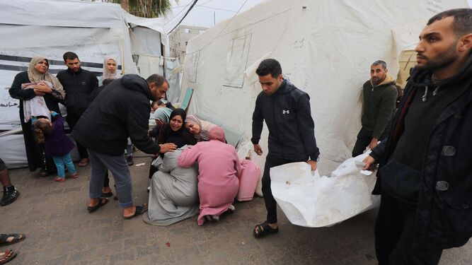 Familiares de los fallecidos en el ataque al campo de refugiados de Al Maghazi lloran mientras esperan recibir sus cuerpos en el hospital El Najar.