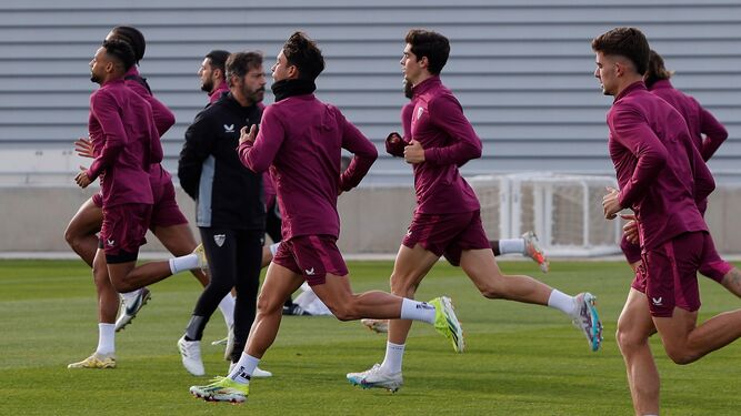 Los futbolistas del Sevilla esprintan en dirección contraria a Quique en el entrenamiento del 6 de enero.