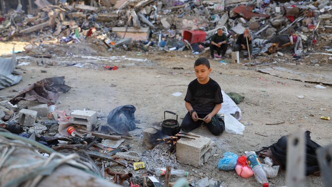Un niño cocina entre escombros en la ciudad de Gaza.