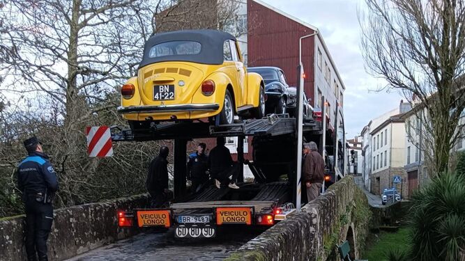 Un trailer cargado con coches históricos queda atrapado durante horas en un puente antiguo sobre un río en Santiago