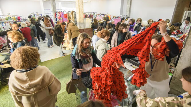 Varias personas buscan entre los trajes de flamenca expuestos en el mercadillo solidario de RedMadre, en una imagen de archivo.