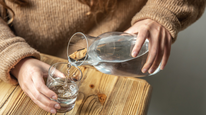 Mujer vertiendo agua en un vaso.