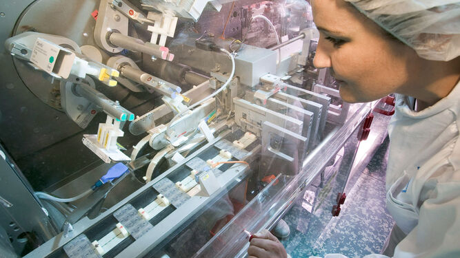 Una trabajadora de una planta de fabricación de medicamentos comprobando la preparación de las cápsulas de un antiviral.