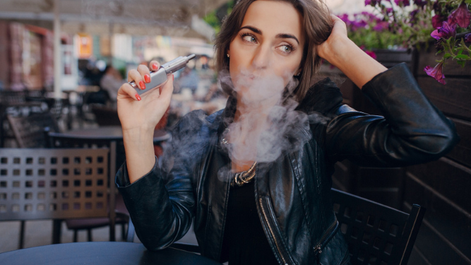 Mujer fumando cigarrillo electrónico en un espacio público.