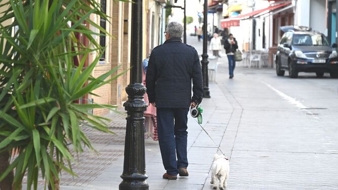 Un vecino paseando a su mascota con bolsas para la recogida de excrementos.