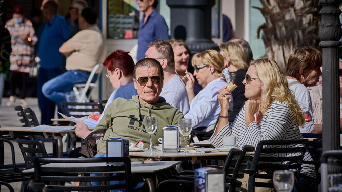 Dos turistas aprovechan el sol del mediodía sentados en la mesa de una cervecería del centro
