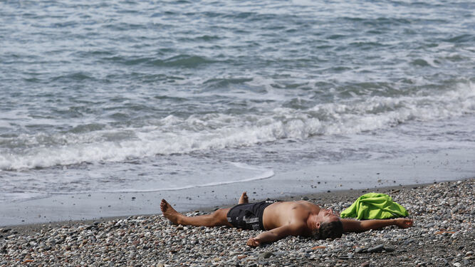 Un hombre se refresca en una playa de Málaga.