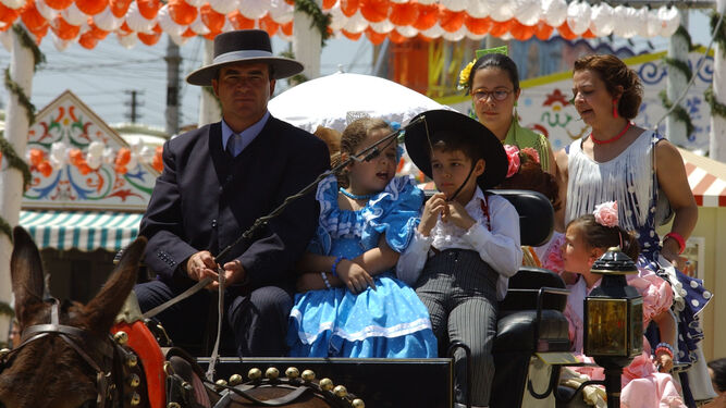 Una familia disfruta, en coche de caballo, de la Feria de Abril.