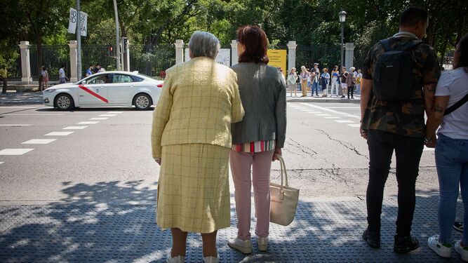 Una mujer acompaña a otra antes de cruzar una vía.