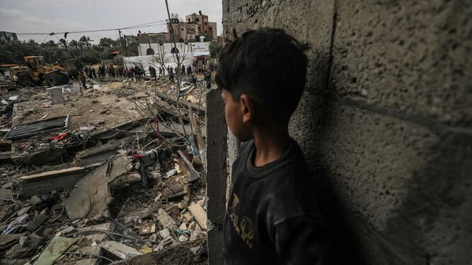 Un chico observa a numerosos palestinos buscar a personas entre los escombros de una vivienda destruida en el campo de refugiados de Al Nusairat.