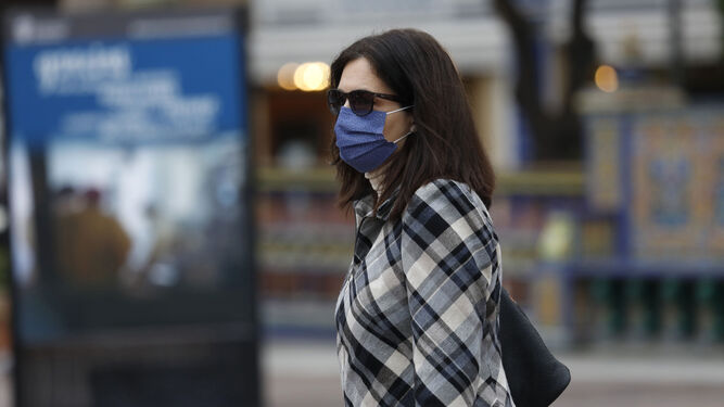 Una mujer, con mascarilla y gafas de sol, dos protectores contra los síntomas de las alergias respiratorias.