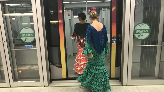 Dos mujeres vestidas de flamenca acceden a un vagón del Metro  con destino a la Feria.